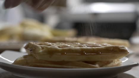 Sprinkling-Cinnamon-On-Top-Of-Freshly-Cooked-Waffles-In-Plate---close-up,-selective-focus