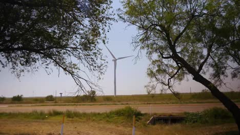 Large-white-wind-turbine-spins-along-a-highway