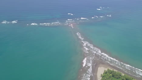 Pull-back-aerial-drone-shot-of-Whale's-Tail,-Uvita-Beach,-Costa-Rica-with-rising-tide