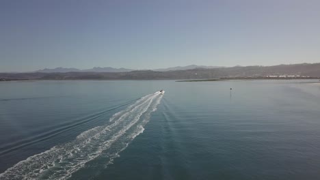Following-aerial-as-motorboat-turns-around-in-Knysna-Lagoon,-S-Africa