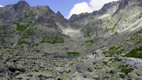 Lago-De-Montaña-Rocosa-Con-Hermosa-Vista-Con-Excursionistas-Pasando-En-Un-Día-Soleado