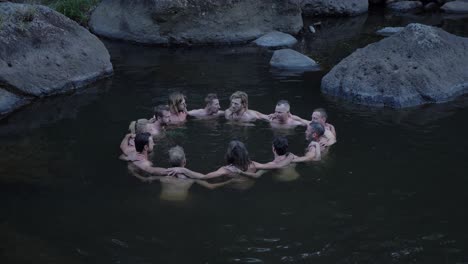 Man-Happily-Sharing-Life,-Experienced,-and-Learnings-On-His-Team-While-In-Huddling-Position-In-Water---Rocky-Creek-In-Mount-Byron,-Queensland,-Australia