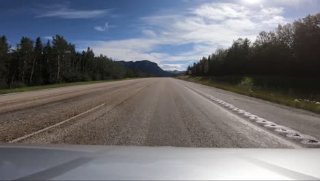 A-POV-Shot-of-A-Car-Driving-Down-An-Empty-Road-Towards-The-Mountains