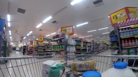 Inside-supermarket-shopping-cart-pushing-trolley-down-middle-aisle-as-customers-shop-during-corona-virus-pandemic