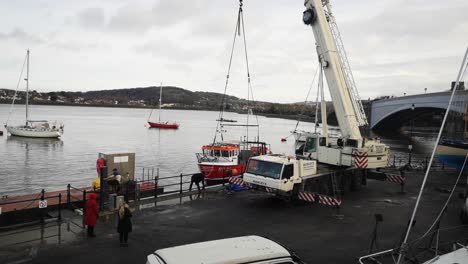 Hydraulic-crane-vehicle-delivery-fishing-boat-on-Conwy-Wales-harbour