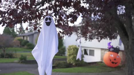 Still-shot-of-a-creepy-Halloween-ghost-decoration-hanging-on-a-tree-and-swaying-with-the-wind-in-a-residential-neighborhood