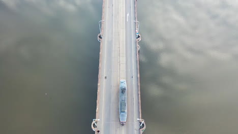 Birdseye-Aerial-View-of-Tram-Moving-on-River-Bridge-With-Sky-Mirror-Reflection
