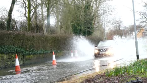 Storm-Christoph-fast-car-driving-rainy-flooding-village-road-splashing-street-cones