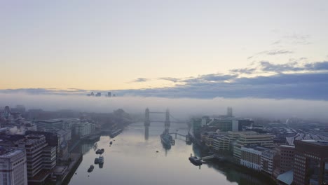 Nebel-über-Der-Tower-Bridge-In-London,-Themse-Bei-Sonnenaufgang,-Canary-Wharf-Im-Hintergrund
