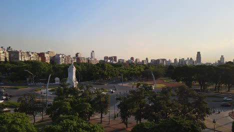 Buenos-Aires-Palermo-city-landscape-roundabout-traffic-and-Palermo-woodland-at-sunset-golden-hour-aerial-rising-right-pan