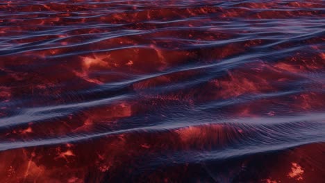 Deep-dark-red-colored-sediment-underneath-slightly-turbulent-ocean-waves-at-sunrise,-seamless-loop