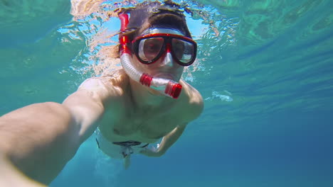 Enthusiastic-Male-Scuba-Diver-with-Red-Snorkel-Swimming-in-Blue-Sea-Water,-Watching-Underwater-Life-and-Sea-Ground-in-slowmo