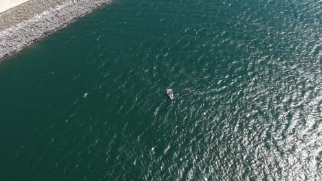 Imágenes-De-Drones-Sobre-El-Lago-Tahoe-Verde-Turquesa,-Panorámicas-Hacia-Abajo-Que-Muestran-Un-Pequeño-Barco-De-Pesca-Navegando-En-El-Agua-Y-El-Agua-Ondeando-Debajo