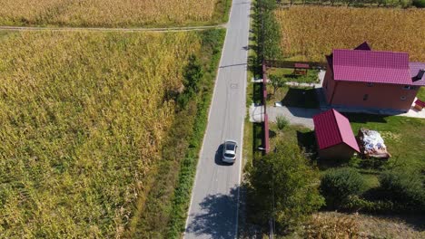 4k-Drone-silver-car-chase-through-a-village,-single-street-with-no-cars