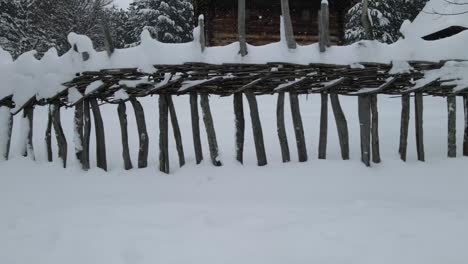 Old-wooden-fence-shot-with-drone,-covered-with-snow