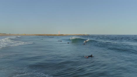 Aerial-shot-surfers-doing-surf-stunts-and-enjoys-riding-the-waves-on-sunny-day,-Algarve