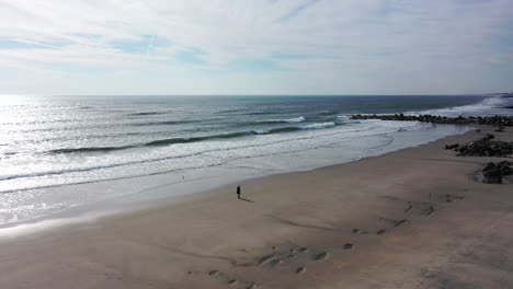 A-drone-view-over-an-quiet-beach-with-one-person-walking-in-the-morning