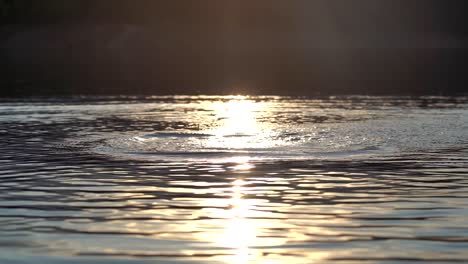 Zeitlupenaufnahmen-Von-Spritzern-Auf-Der-Wasseroberfläche-Vor-Einem-Hintergrund-Von-Sonnenuntergangslicht