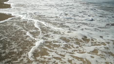 Detail-of-waves-with-wite-foam-at-a-golden-sand-beach
