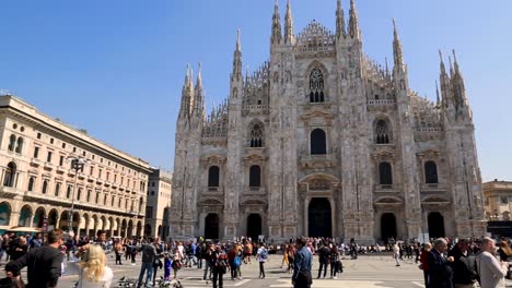 Panning-view-across-Cathedral-Square-revealing-stunning-Milan-Cathedral-and-crowd-of-visitors-on-sunny-summer-day-in-Milan,-Lombardy,-Italy