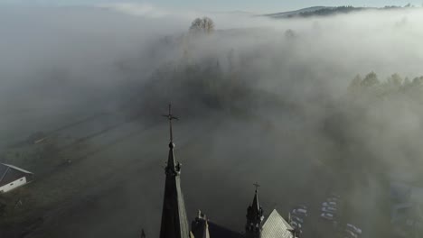Blissful-morning-with-stunning-mist-in-valley-with-breathtaking-church,-aerial