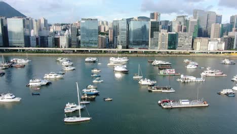 Hong-Kong-marina-with-anchored-boats-and-Kwun-Tong-area-buildings,-Low-angle-aerial-view
