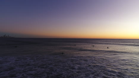 Aerial-drone-flying-out-towards-a-group-of-surfers-waiting-for-the-perfect-wave-during-a-beautiful-sunrise-at-the-very-popular-Burleigh-Heads-Gold-Coast-QLD-Australia