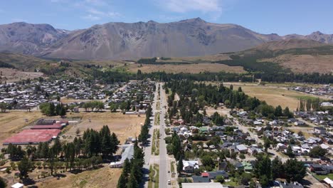 Dolly-in-of-Esquel-town-main-street-surrounded-by-forest-and-Andean-mountains,-Patagonia-Argentina