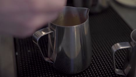 Barista-Puts-Chocolate-Powder-in-Stainless-Frothing-Pitcher
