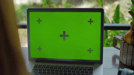 Laptop-with-green-screen-close-up-on-the-table-person-typing-on-keyboard
