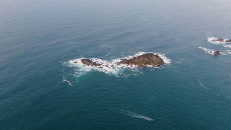 Aerial,-turquoise-Java-sea-water-surround-rocky-islands,-wave-crashing-on-shore