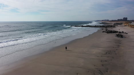 A-drone-view-over-an-quiet-beach-with-one-person-walking-in-the-morning