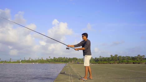 teen-age-boy-fishing-under-blue-sky-sunny-day-beach-slow-motion