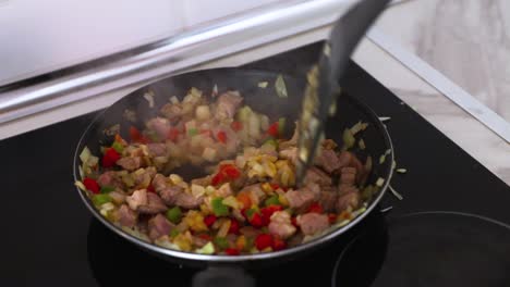 Stirring-onions,-pork-and-peppers-in-a-hot-pan