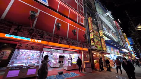 Frente-De-Arcade-Brillante-En-Tokio,-Japón,-Con-Personas-Que-Usan-Máscaras-Pasando