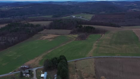 Gloomy-aerial-footage-of-a-farm-in-rural-Rome-Pennsylvania-among-rolling-hills-and-fields-on-a-cloudy-day-with-animals-grazing