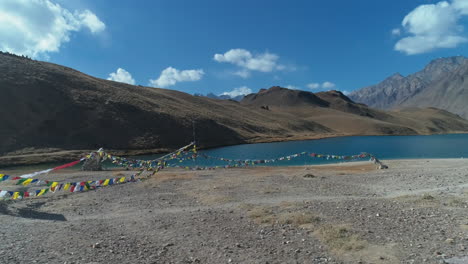 drone-orbiting-close-to-a-beautiful-high-altitude-mountain-lake-with-buddhist-worship-flags-tied-nearby