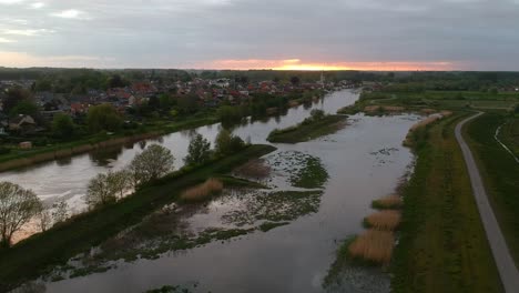 Panoramic-aerial-view-of-swamp-and-houses-in-background-at-sunset