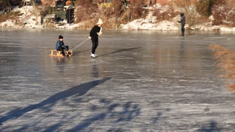 Ice-skating-people-on-the-canal-with-reed-in-the-foreground-panning-to-reveal-more-recreational-activities-at-the-shore