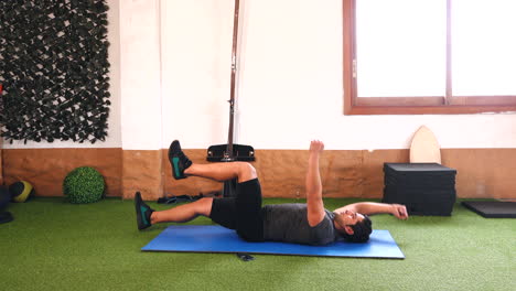 variation-of-abdominal-exercise-with-muscular-trainer-on-blue-mat