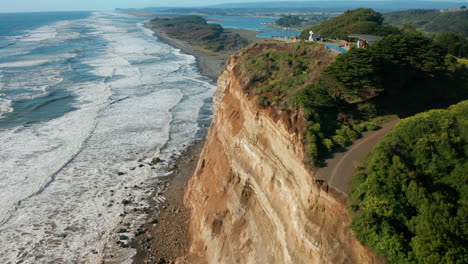 Aerial-landscape-showing-the-coastline-of-Puerto-Saavedra,-Chile-with-a-steep-rocky-cliffs-on-a-bright-sunny-day