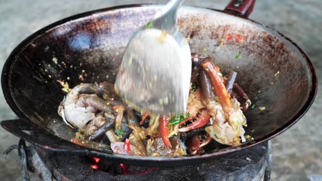 Cooking-fresh-crab-meat-in-wok-style-pan-over-charcoal-fire