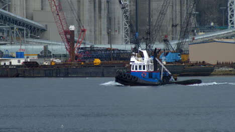 Fischerboot-Segelt-Am-Burrard-Inlet-Vorbei-An-Einem-Industrielager-Mit-Hafenkränen-In-Vancouver,-Kanada