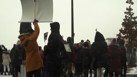 Wide-shot-of-a-crowd-of-people-attending-the-Covid-19-demonstrations-in-Helsinki-with-placards,-cold-weather