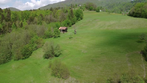 Naturaleza-De-Primavera-Verde,-Antiguo-Granero-De-Heno-Con-Mirador-De-Caza-Al-Lado,-Sombra-De-Nube-En-Movimiento-En-La-Ladera