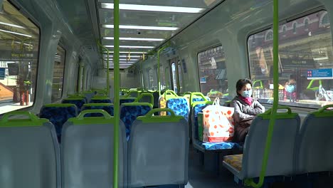 A-woman-in-a-mask-rides-an-empty-train-at-the-height-of-the-global-COVID-19-coronavirus-outbreak