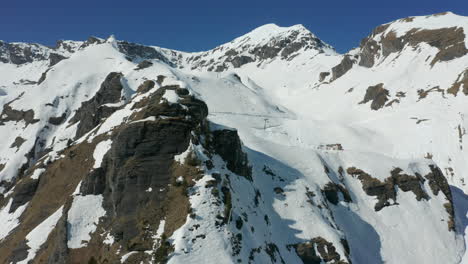 Luftaufnahme-Eines-Schneebedeckten-Felsigen-Berggipfels-Mit-Skiliften-Und-Piste