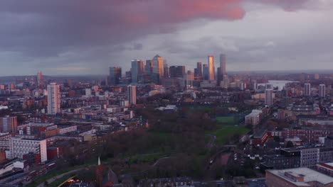Slow-drone-shot-towards-Canary-Wharf-tower-skyscrapers-London-from-north-mile-end-at-sunset