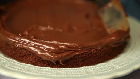 Frosting-the-first-layer-of-a-cake-with-chocolate-icing---close-up-isolated