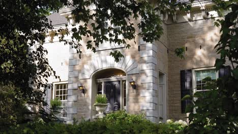 Elegant-front-of-a-stone-mansion-from-the-treed-garden-in-the-front-yard-at-the-Strathmere-Wedding-and-Event-center-in-Ottawa,-Canada